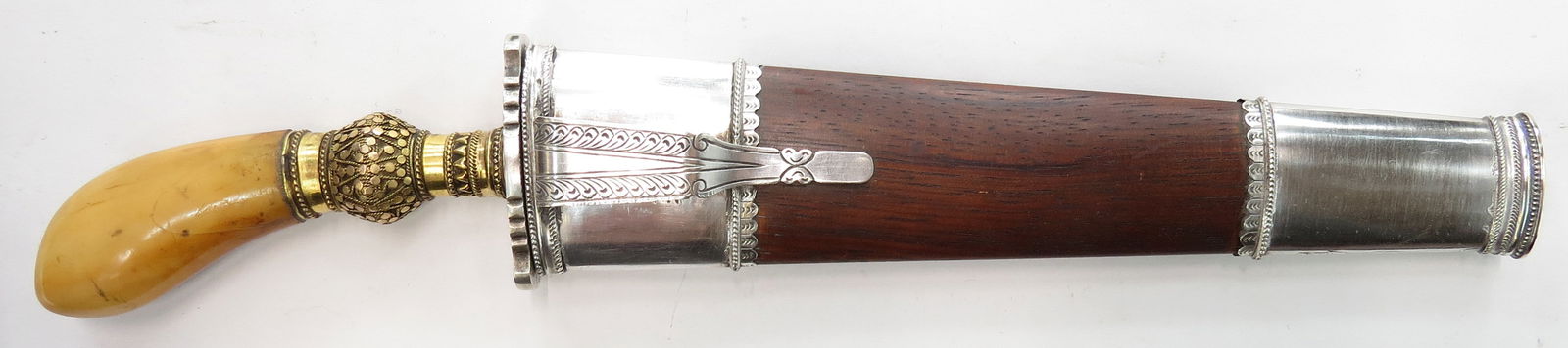 A PHILIPPINES PUNAL GUNONG DAGGER: Moro People of Maguindanao. A fine quality example, with tusk grip and gilded filigreed silver ferrule and engraved silver guard. The handwrought double-edged blade with central ridge and forte panel