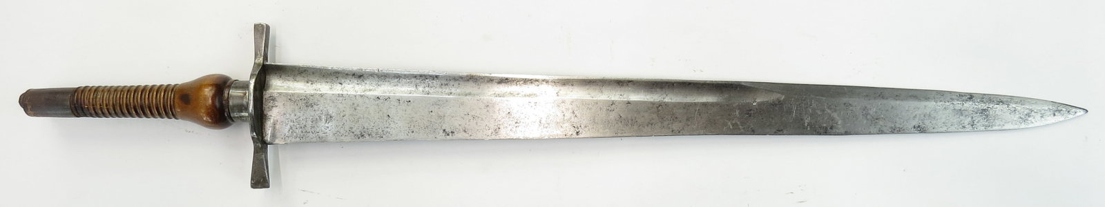 A RARE PLUG BAYONET SHORTSWORD: The iron guard with expanded terminals and ferrule, with turned wooden grip and iron pommel. The massive single-edged blade with back fuller and long false edge. 18th century. Overall wear. Overall le