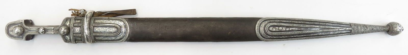 A RARE CAUCASIAN KINDJAL DAGGER: An elegant interpretation of North Caucasian work. Hilt with horn grips mounted in finely engraved and nielloed silver. The double-edged blade with single offset fullers, struck with the makers name O