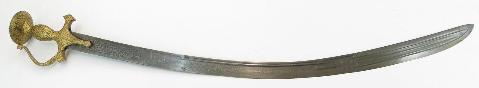 A FINE INDIAN TULWAR SWORD: The Mughal steel hilt with knucklebow finely inlaid overall in intricate flowering vinework in high karat gold, the long, broad, single-edged Persian blade wrought with complex fullering and radiused 