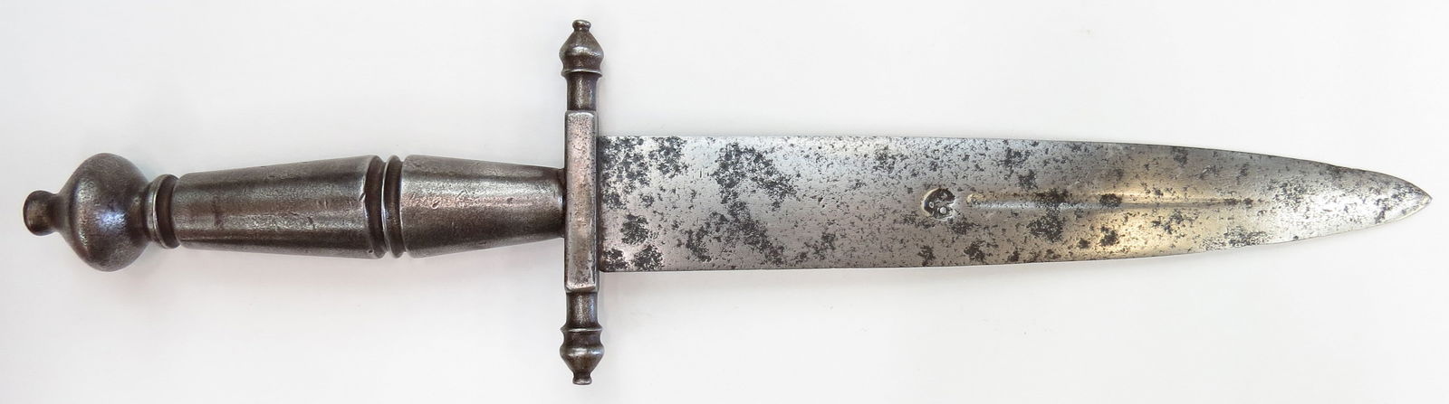 A MEDIEVAL DAGGER: The steel blade straight and double-edged, with a short central fuller and struck with a makers mark on the obverse. The guard and grip likewise of steel, with expanded and beaded quillon terminals an