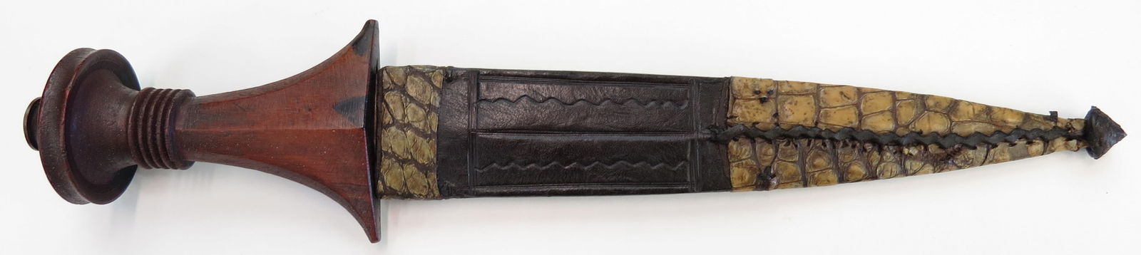 A RARE INSCRIBED SUDANESE DAGGER: An above average example, with ebony grip and broad, engraved blade, inscribed AL KHARTOUM 1317 (1899 C.E.) and OMDURMAN YEAR 99 (assumed 1899.) In its leather scabbard with white crocodile mounts. Da