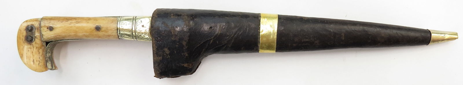 AN AFGHAN CHOORA DAGGER: With characteristic hooked pommel and engraved bolsters with straight, tapering blade. In its leather-covered wooden sheath. Late 19th century. Light wear. Overall length 33 cm / 13". Condition II