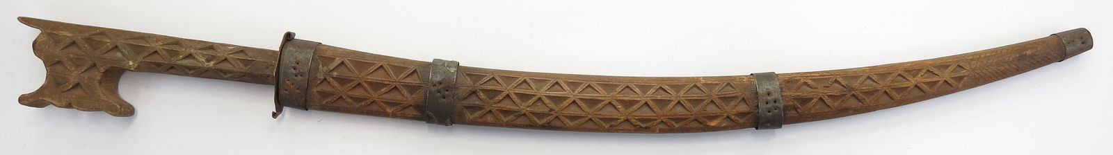 A NORTH AFRICAN NIMCHA DAGGER: The wooden mounts carved overall, with metal band. With characteristic scrolled and hooked pommel and recurved guard. The curved blade with engraved motifs. Early 20th century. Minor wear. Overall len