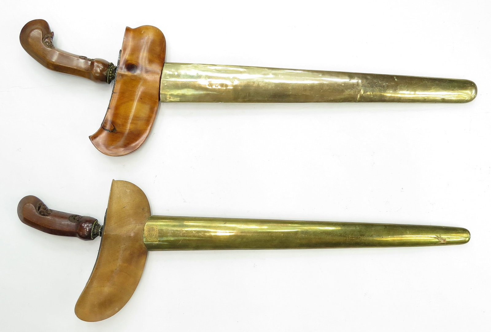 TWO INDONESIAN KRIS SWORDS: Of characteristic form, the grips and scabbards carved of exotic hardwood with good patina and brass pendoks. With intact mendaks, the waved, double-edged blades showing complex and active damask. 20t