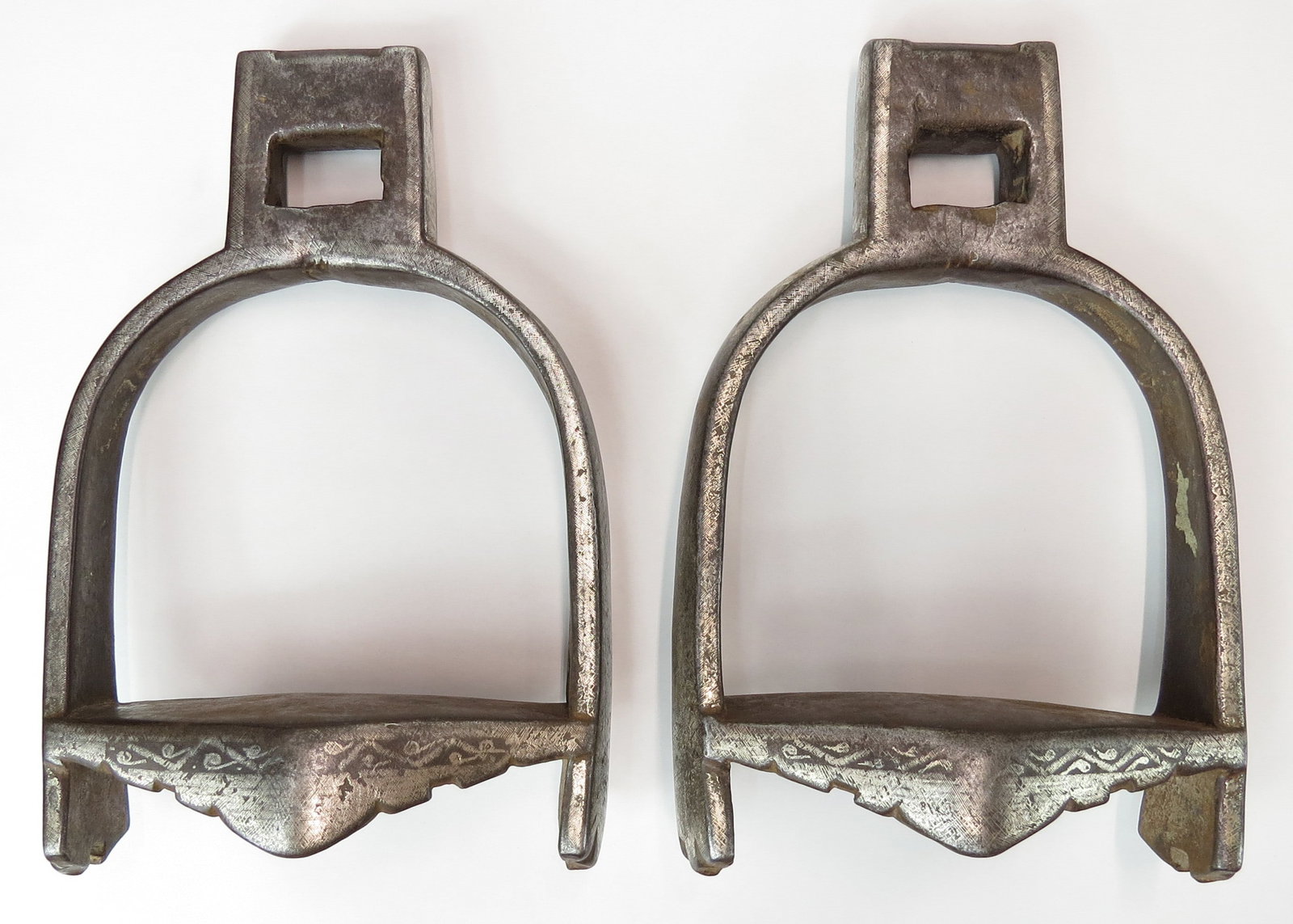 A RARE PAIR OF CENTRAL ASIAN FIGHTING STIRRUPS: Wrought entirely of steel with deeply-profiled tread plates designed for kicking and inlaid overall with silver. First half of the 19th century. Worn. Overall 23 cm / 9 1/8?. Condition II