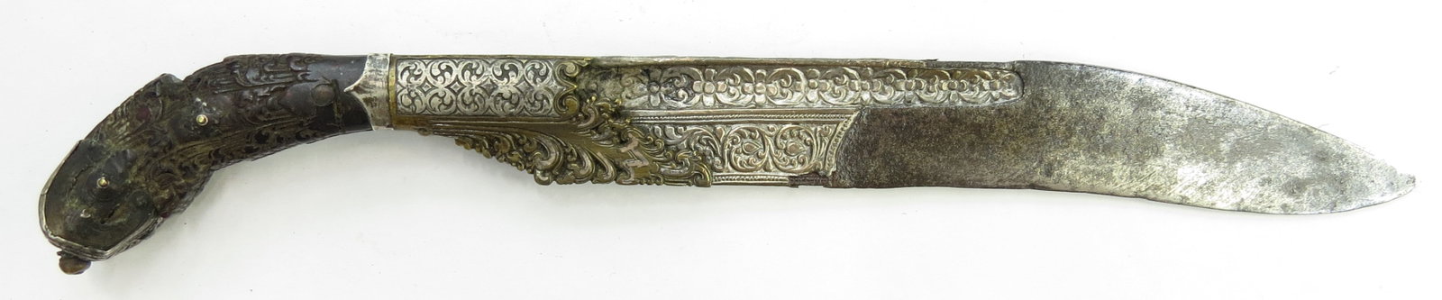 A SRI LANKA PIHA KAETTA KNIFE: Of typical form, with silver-mounted ebony grip intricately incised and engraved overall. Heavy, single-edged blade with deep fullers and extensive silver inlay. 19th century. Worn, losses. Overall le