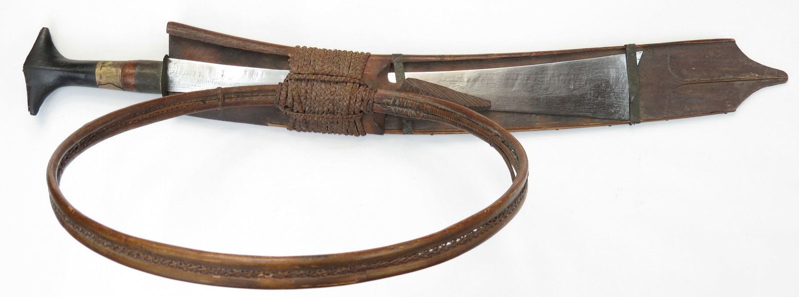 A KACHIN NAGA HEADHUNTER DAO SWORD: Kachin work, the hilt with applied brass pommel, the grip wrapped with brass ferrule. The stout, chisel-edged blade with characteristic flared tip, with traces of layer-forged construction visible nea