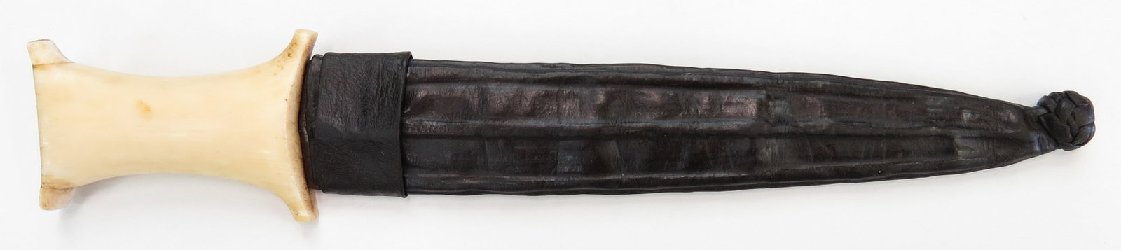 A SUDANESE DAGGER: An uncommon example, with elephant grip showing Ottoman influence and broad, double-edged blade with central ridge, In its leather scabbard. Mid-19th century. Worn overall, repairs to grip. Overall le