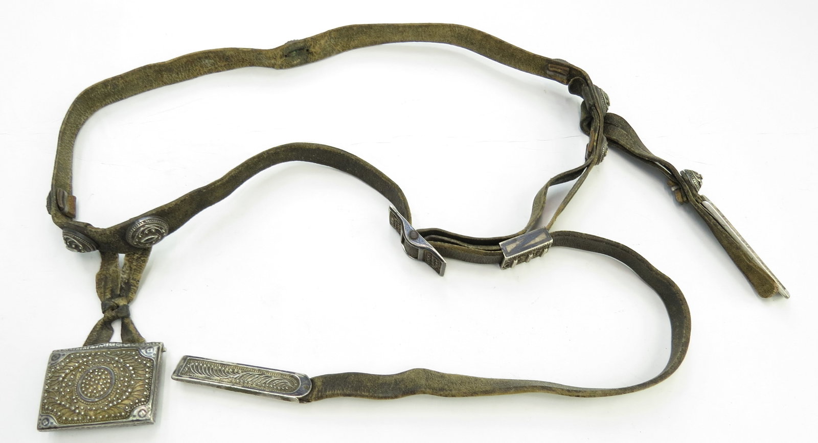 A CAUCASIAN COSSACK DAGGER BELT: Fine workmanship, the brown hide band with two pendent straps, heavily embellished with 13 solid silver mounts, each showing filigree, niello and gilding, with Russian hallmarks. Latter 19th century. 