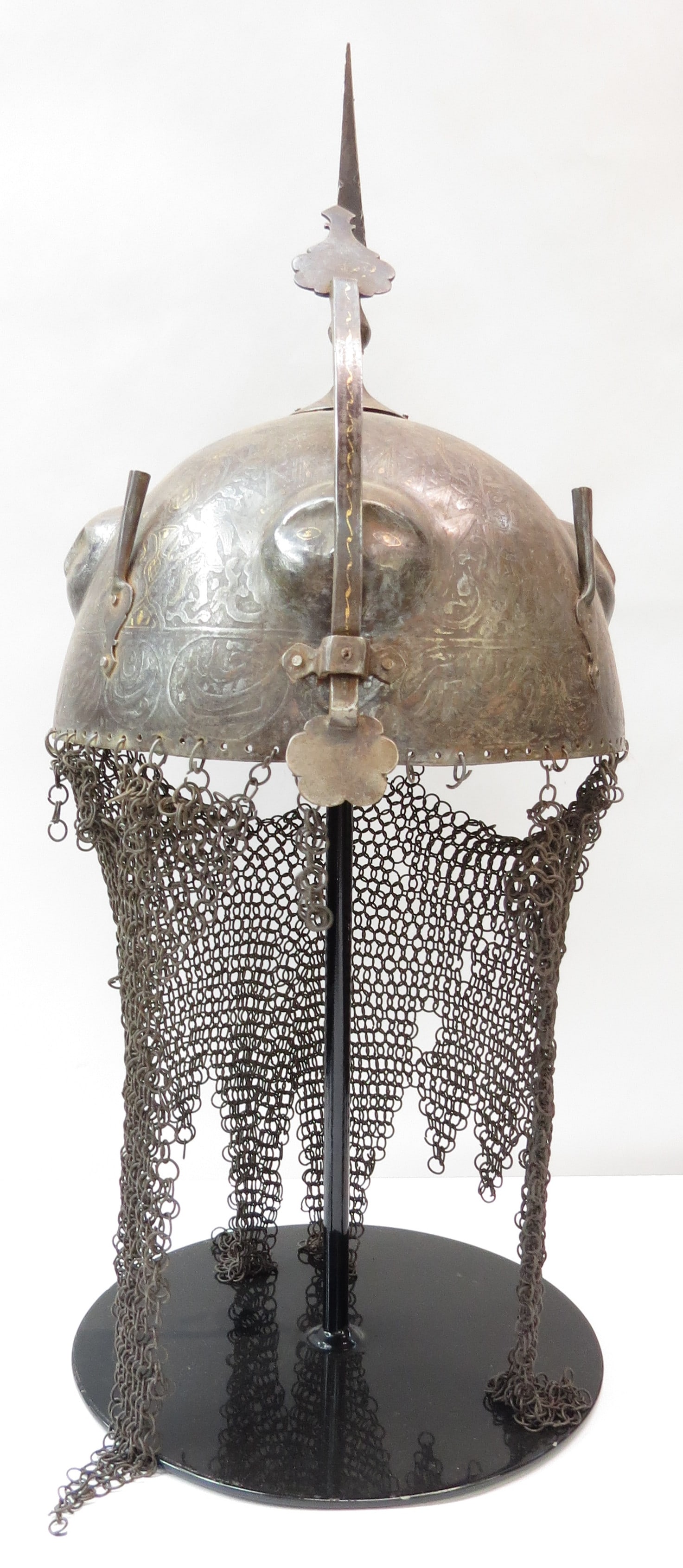 A PERSIAN KULA KHUD HELMET: A rare Qajar Dynasty example with anthropomorphized suns wrought into the bowl, and etched overall with scenes from the Persian Book of Kings, surmounted by a characteristic spike, together with plume