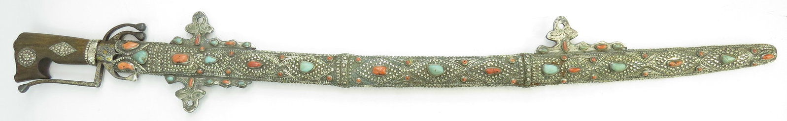 A FINE PRESENTATION MOROCCAN SAIF SWORD: The characteristic massive grip with scrolled pommel carved of a single large section of rare rhino horn with engraved silver ferrule and filigreed silver bosses. The distinctive steel guard forged wi