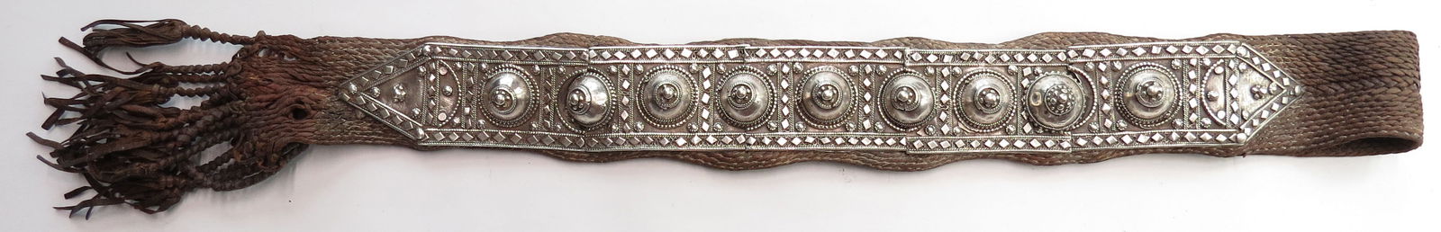 A RARE OMANI SILVER MUSKET SLING: Of numerous layers of braided leather terminating in a series of knotted tassels and set with finely wrought and filigreed silver. 19th century. Slight wear. Overall length 110cm / 43 1/3?Condition II