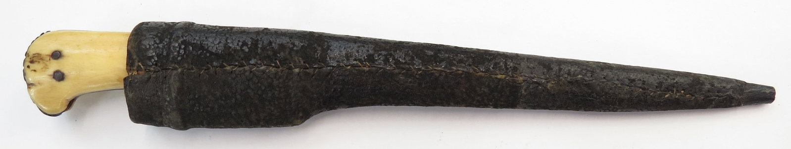 AN AFGHAN PESH QABZ DAGGER: Of characteristic form, the bone grips with fine patina, the blade with strong, recurved T back and chamfered edge tapering continuously with areas of fine black Persian wootz visible. In its leather-