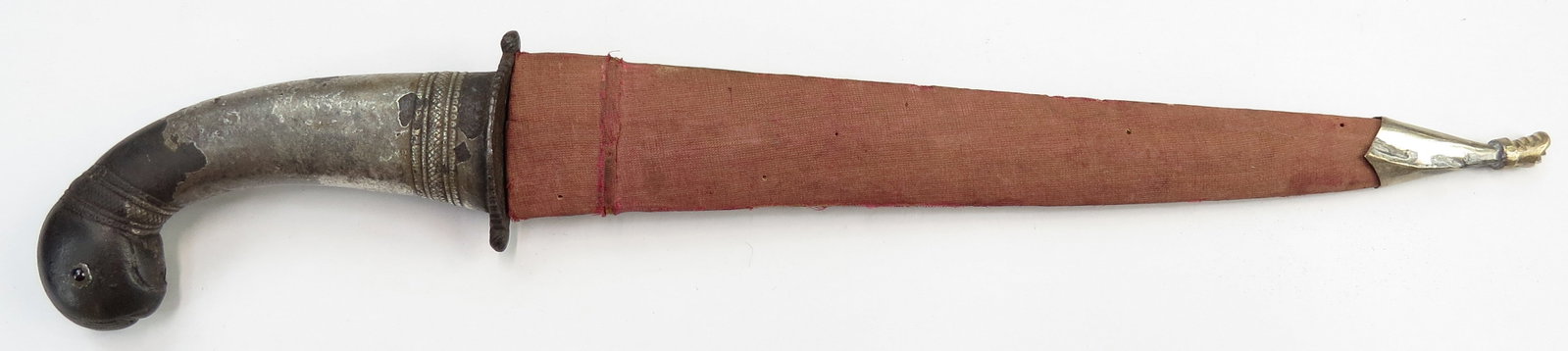 AN INDIAN KHANJAR DAGGER: Mughal work, the iron grip terminating in a fully-modelled parrot head with inlaid ruby eyes, retaining much original heavy silver overlay. The fine blade of flattened hexagonal section with central r