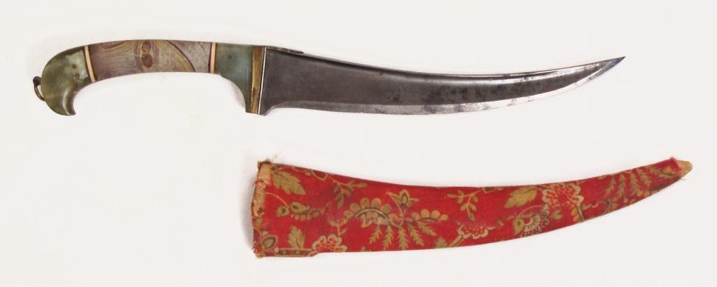 A NORTH INDIAN DAGGER: The grips of variegated hardstone with elephant bands and brass mounts.The curved, T-backed blade with chamfered edge.In its fabric-covered wooden scabbard.Mid-19th century. Overall length 31 cm. Cond
