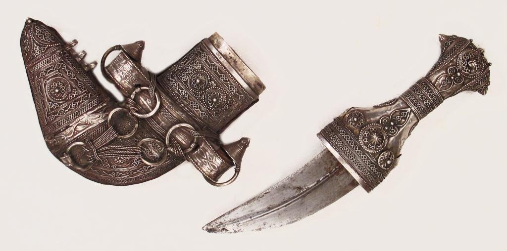 AN OMANI CHILD’S KHANJAR DAGGER: Of typical form, mounted entirely in filigreed silver. The curved, double-edged blade with central rib, wooden scabbard covered entirely in filigreed silver en suite with the hilt. Second half of the