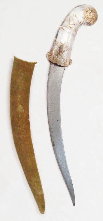 A MUGHAL ROCK CRYSTAL-HILTED KHANJAR DAGGER: The grip finely carved, with rolled pommel and lotus motifs in relief. The recurved, single-edged blade forged of actively-patterned wootzdamascus steel. In its velvet-covered wooden scabbard.First ha