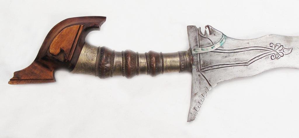 A MORO DATU'S KRIS SWORD: Maguindanao work, the elaborate junggayan hilt typically carried by a datu or noble, with kakatua-form pommel and silvered mounts with okir engraving. The substantial 13-waved blade engraved at the fo