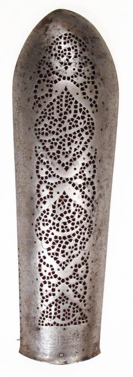 A PERSIAN QAJAR DYNASTY BAZUBAND ARMGUARD: Raised from a single plate and pierced overall in Qur’anic inscriptions in cartouches, backed with red velvet. Traces of later etched borders.Latter 18th century.Lining worn.Overall length 31 cm. Co