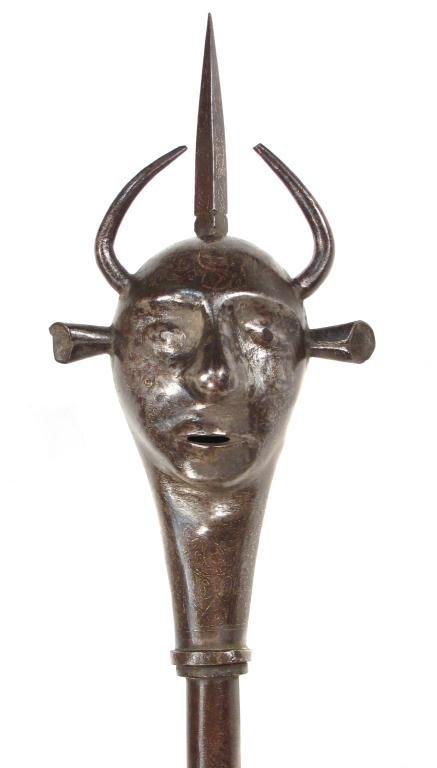 A PERSIAN QAJAR DYNASTY MACE: Of steel, wrought in the form of a devil’s head with prominent horns, eyes, ears and nose, on its steel haft.Latter 19th century. Weapons such as these were popular in Muharram Mourning ceremonies. 