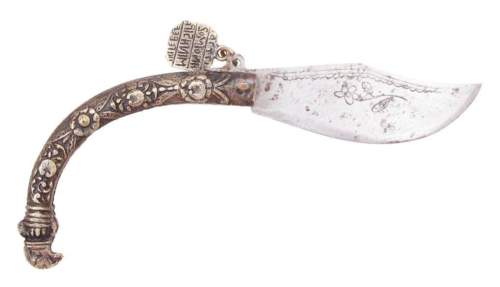 A BALKAN CLASP KNIFE: The curved case of brass with baroque motifs and hooked terminal, the broad blade with clipped tip etched with a flower on one side and a fish on the other. With a rectangular brass seal attached, con