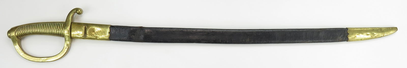 A SPANISH M1840 ARTILLERY BRIQUET SWORD: With characteristic brass hilt and curved, single-edged blade with back edge etched FCA DE TOLEDO 1875. In its original leather scabbard with brass mounts. 19th century. Minor wear. Overall length 83.