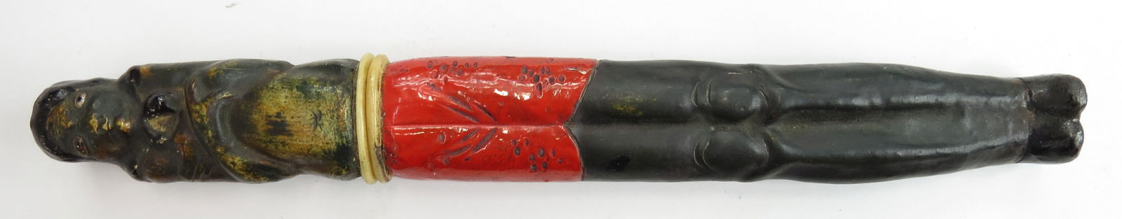 A JAPANESE VOTIVE TANTO DAGGER: With fanciful wooden mounts carved in the form of Daruma, the Buddhist monk associated with luck. Wearing a black lacquer hood with peaceful countenance and arms crossed over his chest, and a red-lacq