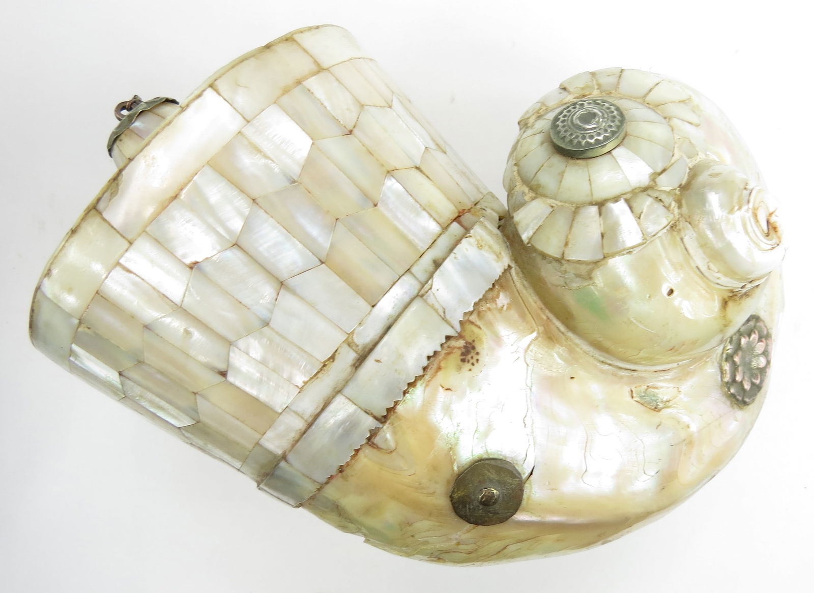 AN INDIAN BARUTDAN POWDERHORN: The body formed of a large, polished sea snail shell, the upper section formed of additional profiled shell plaques. The spout and cap of silver. 18th c. Minor losses, stable crack to shell. Overall l