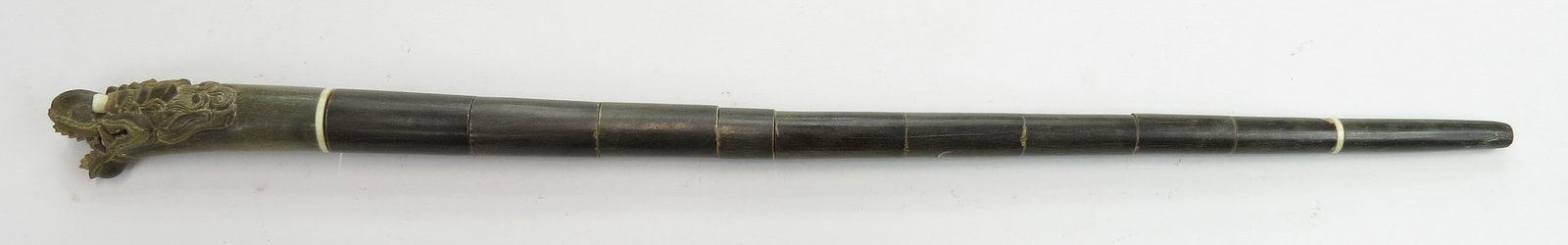 A DUTCH-INDONESIAN OFFICERS SWAGGER STICK: Fine Indonesian work for a Dutch officer, the grip superbly carved in horn as a dragons head with staring bone eyes. The segmented horn shaft with bone bands enclosing a straight, double-edged blade.