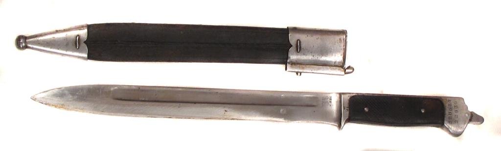 A M 1889 KRAG JORGENSEN BAYONET: With rubber grips, struck with numerals at pommel and maker?s mark at forte. In its leather sheath with steel mounts.Late 19th-early 20th century.Overall length 37.4 cm. Condition II