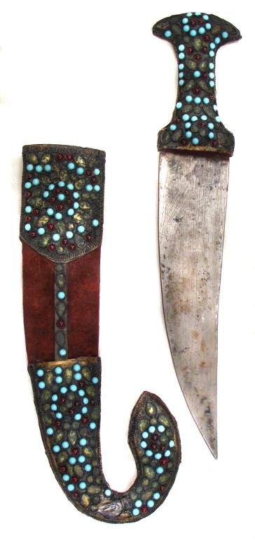 A SYRIAN KHANJAR DAGGER: Typical of Ottoman provincial work, the gilded tombak mounts heavily filigreed on the obverse and set with turquoise and garnet stones or glass jewels, and elaborately engraved in baroque motifs on th