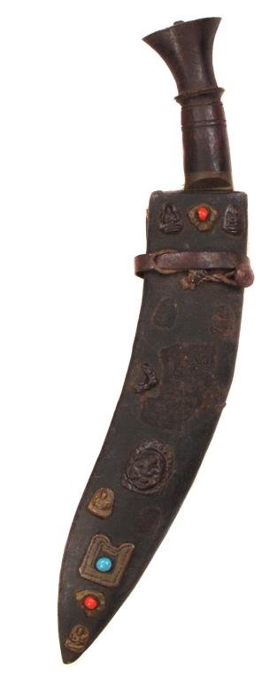 A NEPALESE KUKRIE DAGGER: Of characteristic form, with applied decorations on scabbard.First half of the 20th century.Some losses to scabbard.Overall length 44.5 cm. Condition IV