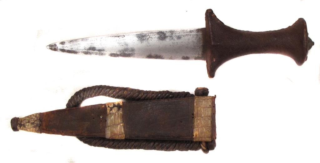 A SUDANESE ARM DAGGER: With leather-covered wood handle and broad blade, the leather scabbard with braided armband. Late 19th century .Overall length 28 cm. Condition I