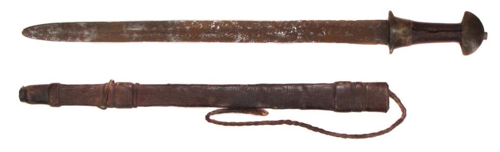 AN AFRICAN MANDING SWORD: With iron mounts and blade, in its leather scabbard. Mid-19th century.Considerable wear. Overall length 61.5 cm. Condition IV