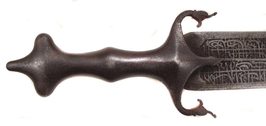 A PERSIAN BROADSWORD: Reflecting the neoclassicism prevalent during the reign of Nasr al-Din Shah, the symmetrical steel hilt with trilobate pommel and scrolled quillons. The massive, straight, double-edged blade etched ov