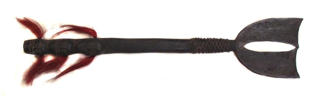 A RARE NAGA DAO SWORD: Of a form seldom encountered, with handwrought steel double blade. Set in a hardwood handle carved with human heads and decorated with tufts of colored hair, and rattan binding. Latter 19th century.Wo