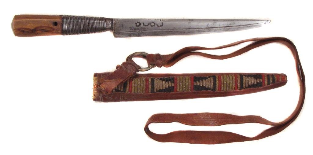 AN ALGERIAN DAGGER: The faceted grip with silver wire wrap to base, and single-edged blade struck with marks. In its embroidered leather scabbard.Mid-19th century.Overall length 29.7 cm. Condition II