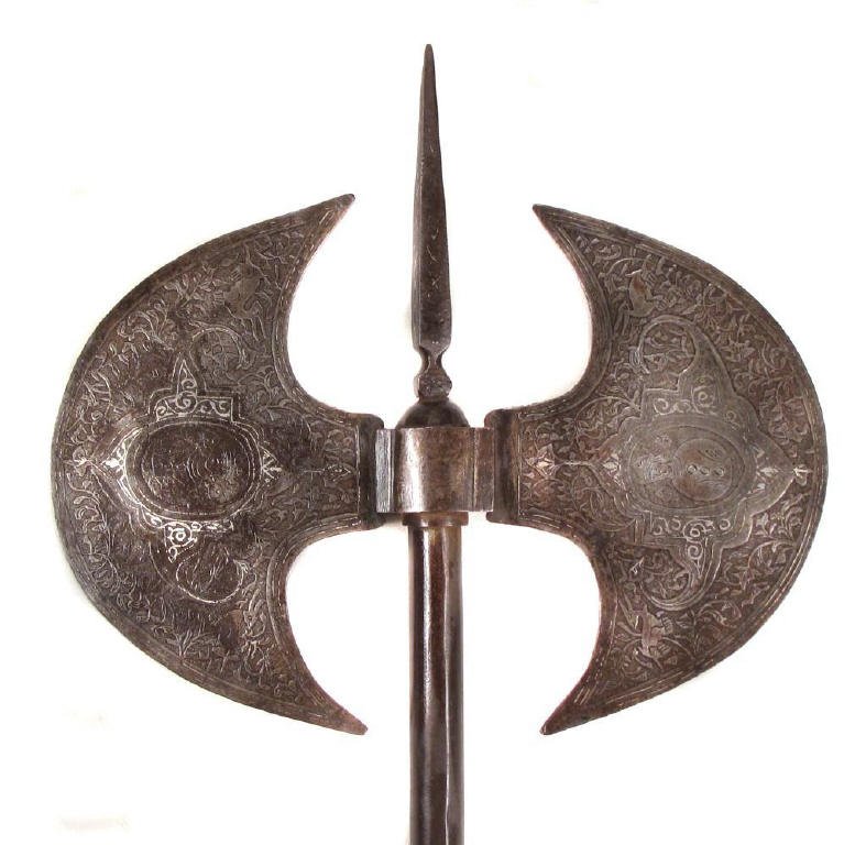 A PERSIAN QAJAR DYNASTY BATTLEAXE: The double crescent-form heads etched with elaborate floral panels surrounding birds and a king in the central cartouche on each side, and heightened with silver inlay, as is the elongated topspike. O