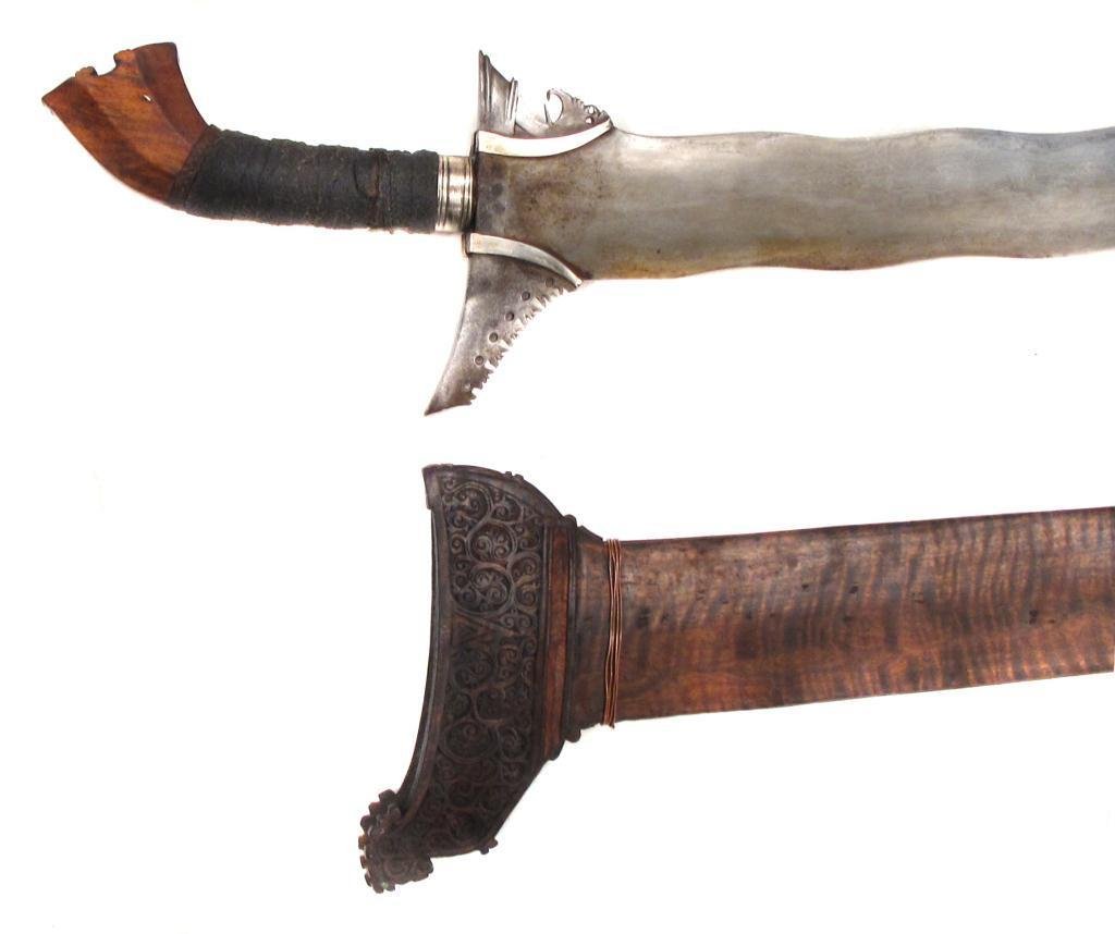 A MORO KRIS SWORD: A fine example with exotic hardwood grip, the pommel flared and scrolled, with cord-wrapped grip and silver ferrule which neatly retain the silver baka-baka. The broad, waved blade with separately-app