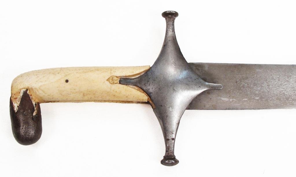 A PERSIAN QAJAR DYNASTY SHAMSHIR SABER: A large example, with antler grips and faceted steel pommel cap and guard forged of Persian Kara Khorassan black wootz. The robust, lightly curved and single-edged blade likewise forged of actively-pa