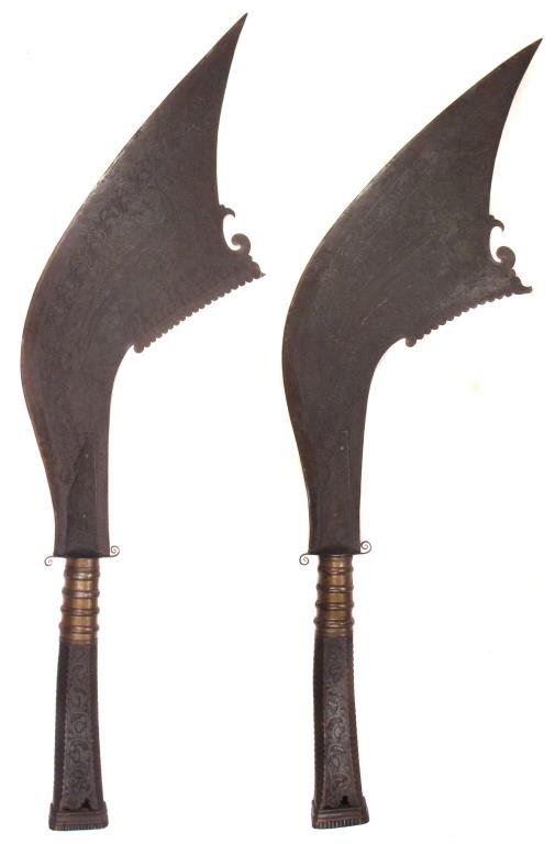 A MASSIVE PAIR OF MORO BEARING SWORDS: A matched PAIR of enormous processional weapons carried before a sultan or datu, in the form of panabas axes. The blades handforged, with chamfered cutting edges and profiled spines, each engraved ove