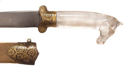 MUGHAL ROCK CRYSTAL-HILTED KHANJAR DAGGER: Very finely carved, the pommel terminating in a fully-modeled antelope?s head, the bilobate steel guard inlaid in gold floral motifs. The lightly recurved, single-edged blade forged of silver-gray woo