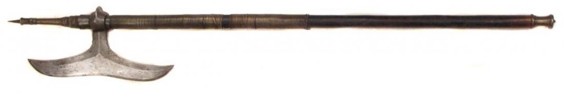 A RARE INDIAN BATTLEAXE: A form endemic to the Bhil people of Central India, the steel head forged with concave edge, the socket wrought with a pronounced flange. On its hardwood haft with iron and elaborately-modeled brass m
