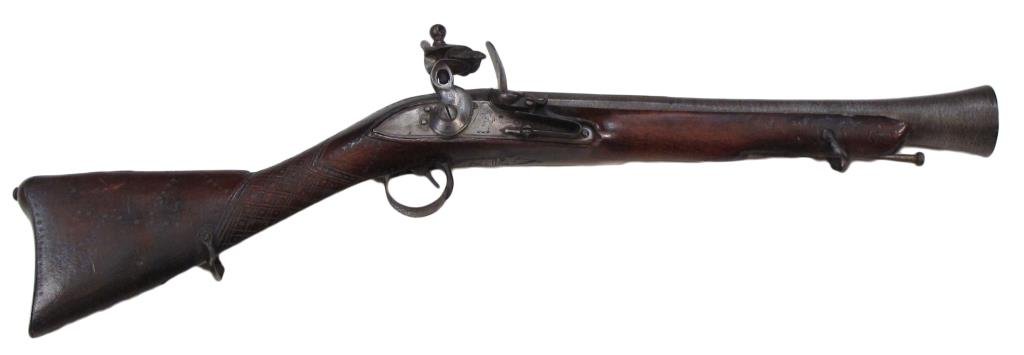 AN OTTOMAN BLUNDERBUSS: A massive example, the hardwood stock with carved geometrical decoration and well-wrought, profiled iron furniture, the large British flintlock mechanism with Tower marks. With superior Ottoman patter
