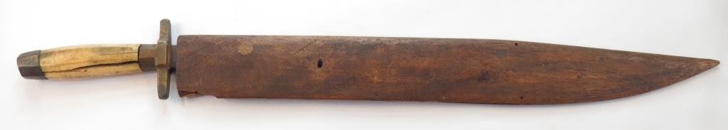 A PHILIPPINES SWORD: Katipunan-era work of Visayan itak form, the blade very well wrought, the guard and pommel of brass with faceted bone grip. In its wooden scabbard. Late 19th-early 20th century. Grip with stable crack
