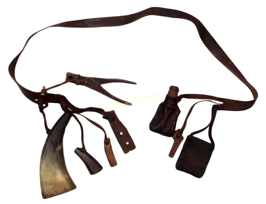A CONTINENTAL FLINTLOCK MUSKETEER€™S BELT: The leather belt supporting a horn flask, priming flask, measures, a scoop, grease pouch and bullet mold._x000D_ First half of the 19th century. Buckle lacking. Overall length 108 cm. _x000D_ Conditio
