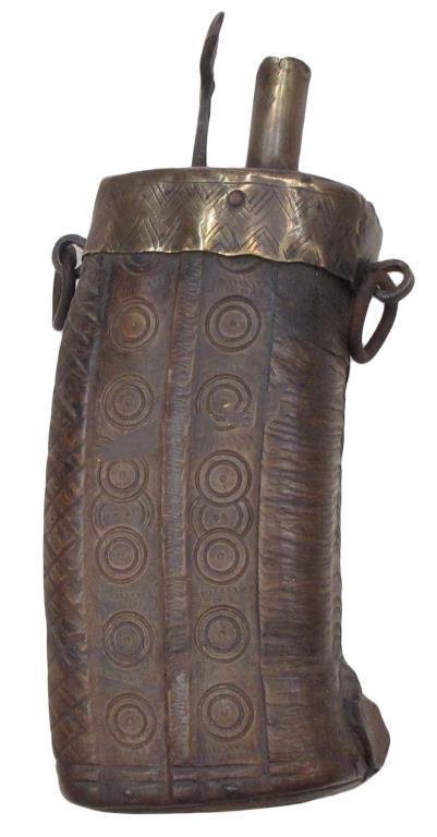 A MOROCCAN POWDERHORN: Of characteristic form, well-made from a large section of horn with incised circular motifs, the cap and spout of brass with cutoff. Iron suspension rings. First half of the 19th century. Light wear.