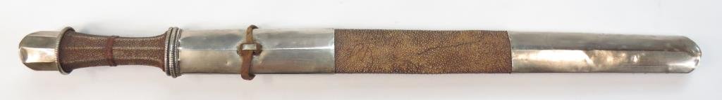 A HIMALAYAN DPA' DAM SWORD: A rare example of Tibetan or Bhutanese workmanship, the waisted grip covered with rayskin, the guard and pommel of silver. The characteristic blade straight, broad and single-edged with radiused tip. 