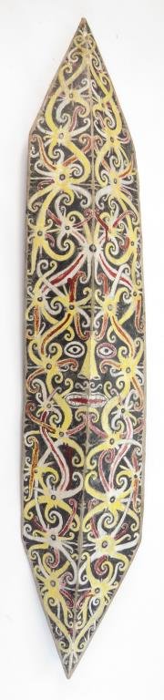 A RARE DAYAK SHIELD: Of characteristic form, carved from a single large section of wood with raised central ridge. Painted overall in red, white, and yellow on a black ground, depicting an aso dragon in the center with st